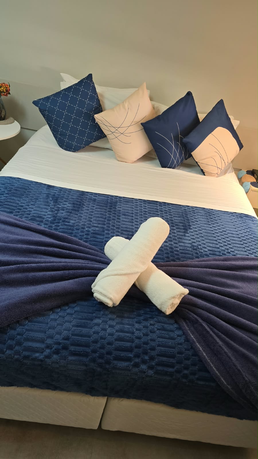 Cama preparada pela equipe, com enxoval azul e toalhas organizadas